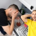 uomo disperato con lavandino della cucina otturato e un altro sorpreso