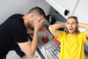 uomo disperato con lavandino della cucina otturato e un altro sorpreso