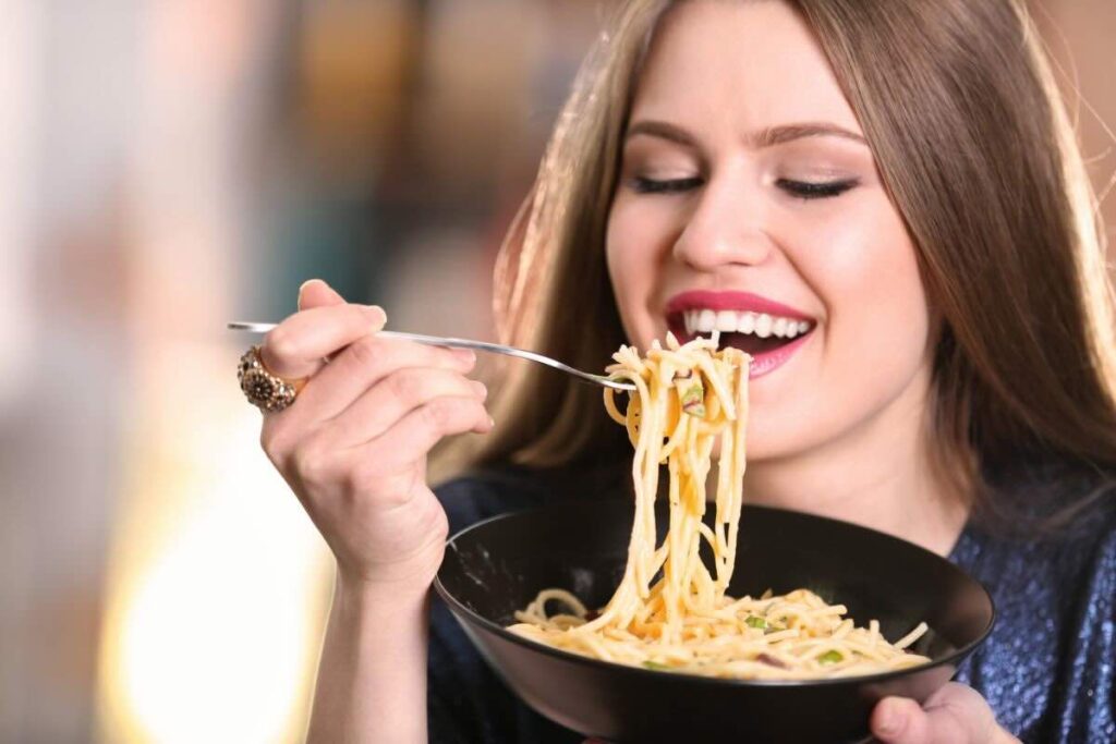 Donna mangia spaghetti, sorridente