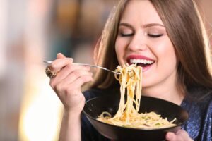 Donna mangia spaghetti, sorridente