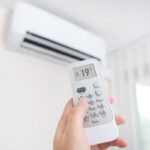 mano con telecomando e condizionatore