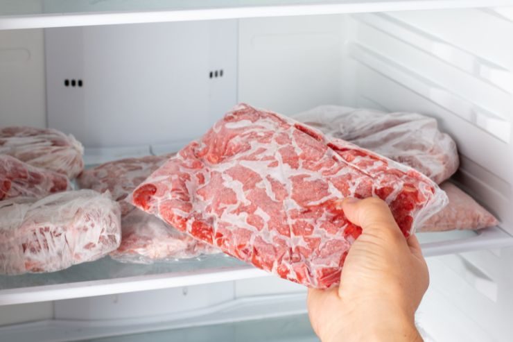 donna che prende dal freezer una fetta di carne